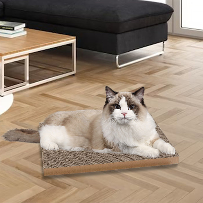 Reversible cat scratching board in brown and beige, with a fluffy cat lounging on it in a cozy living room setting.