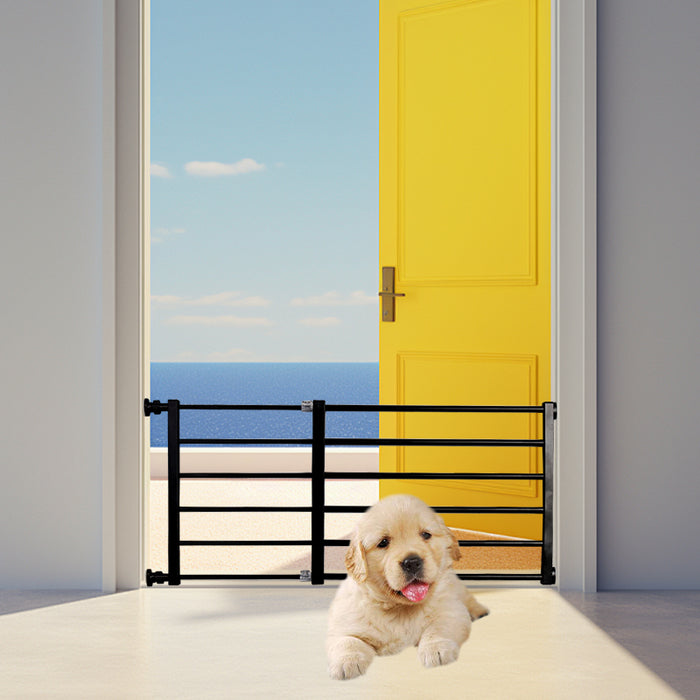Retractable black pet safety gate positioned at an open yellow door, with a golden retriever puppy lying on the floor.