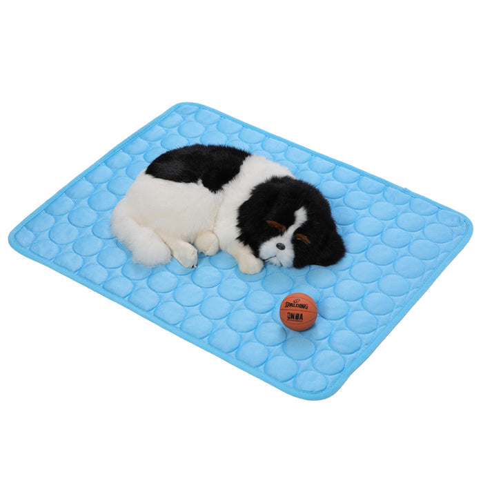 A fluffy black and white dog rests on a light blue self-cooling pet mat, next to a small orange ball.